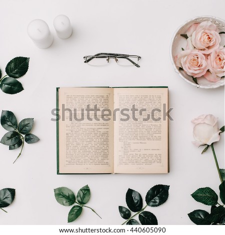 Opened book, glasses, pink roses on white background. Flat Lay