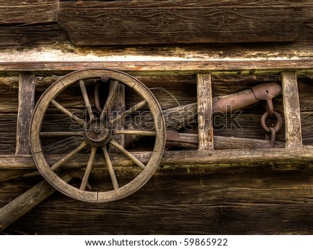 weathered wall of old barn with wooden ladder and wood coach wheel