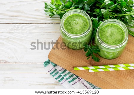Healthy green smoothie in a mason jar mug on rustic wooden background