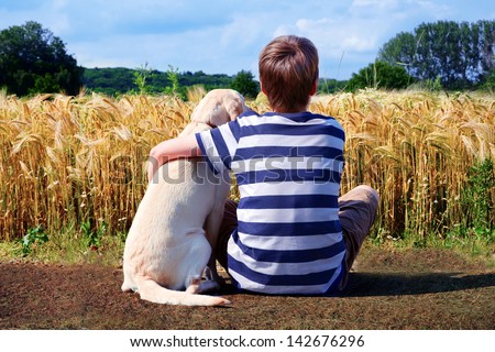Boy with pet dog, corn field in background
