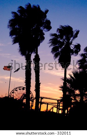 Palm trees, ferris wheel, roller coaster and U.S. flag at sunset