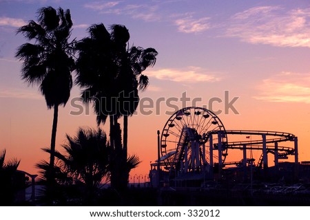 Palm trees, ferris wheel, and roller coaster at sunset