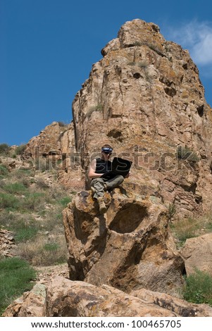 The man with the laptop sits in beautiful mountain district