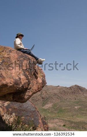 Man with the laptop sits on the brink of breakage. Vertical frame