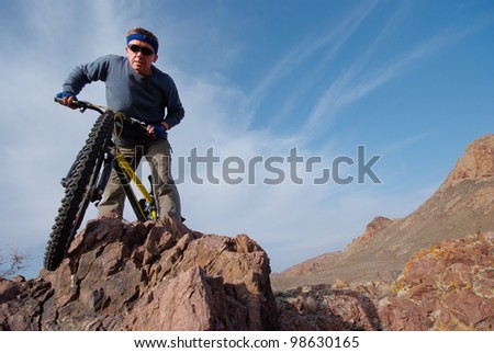 Bicyclist on background sky overcomes obstacle. Horizontal frame