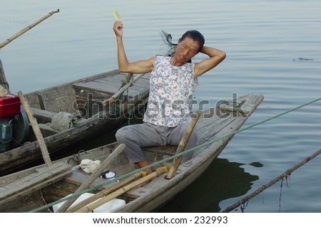 a women fisher combing her hair on her boat early in the morning. She has strong arms