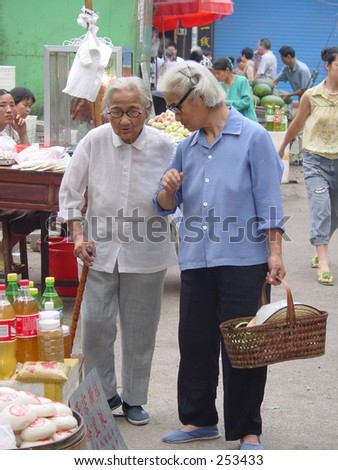 an old woman helped another elder woman walking through market. Photo taken in Zhejiang, China. The elder one was in her nineties.