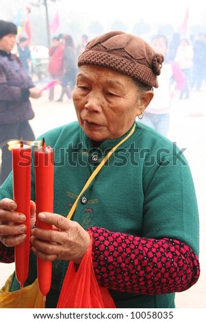 an old lady who is worshiping the deity by offering candles