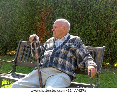 old man enjoys sitting on a bench in his garden