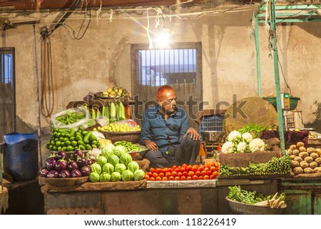 BIKANER, INDIA - OCTOBER 23: Seller at the vegetable night market on October 23, 2012 in Bikaner, India. They sell fresh vegetables from the farms in Rajasthan as well as imported fruits.