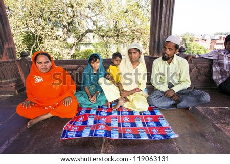 DELHI, INDIA - OCTOBER 16: A family of worshipers rest on the courtyard of Jama Masjid Mosque on October 16, 2012 in Delhi, India. Jama Masjid is the principal mosque of Old Delhi in India.