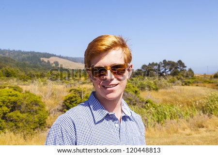 cool teenage boy with sunglasses walks happy on the meadow