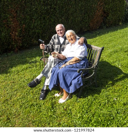 elderly couple sitting in their garden and enjoy life