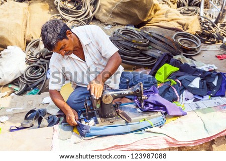 ORISSA, INDIA - NOV 10:Indian men tailors run their sewing machines in the shade at the weekly market on Nov 10, 2009 in Orissa, India.