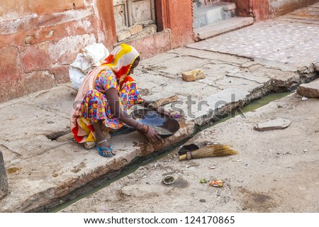BIKANER, INDIA - OCT 24: woman tries to find gold dust in the canalisation of the gold smith area on October 24, 2012 in Bikaner, India.