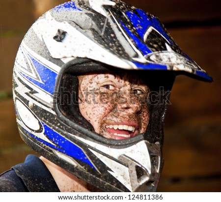 young boy is faszinated by quad driving and enjoyes is, his face is dirty from mud