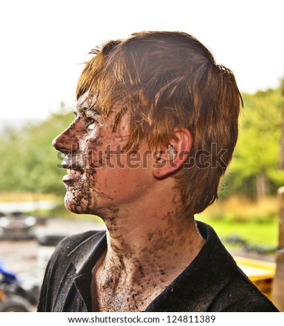 young boy is faszinated by quad driving and enjoyes is, his face is dirty from mud