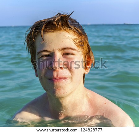 boy with red hair is enjoying the clear warm water at the beautiful beach