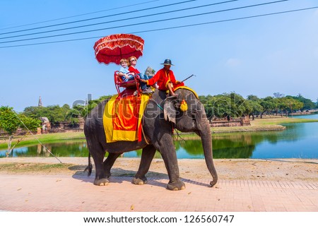 AYUTTHAYA, THAILAND DEC 23: unidentified tourists ride on an elephant in the Historical Park on DEC 23, 2009 in Ajutthaya, Thailand. It is called a must and costs about 1000 BATH for 30 min.