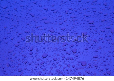 red pattern of raindrops at a metal surface of a car