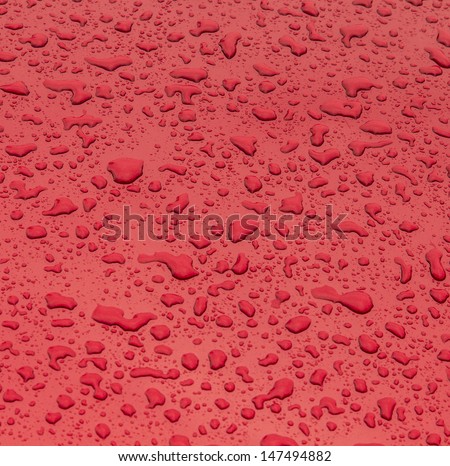 red pattern of raindrops at a metal surface of a car
