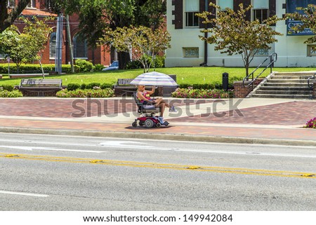 LAKE CHARLES, USA - AUG 9:   lady rides in her electric wheelchair on Aug 9, 2013 in Lake Charles, USA. Electric wheelchair was invented after WW2 by George Johann Klein for the injured war veterans.