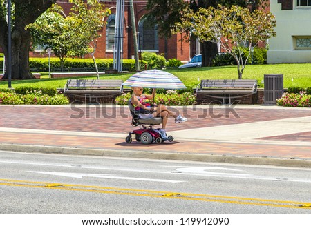 LAKE CHARLES, USA - AUG 9:   lady rides in her electric wheelchair on Aug 9, 2013 in Lake Charles, USA. Electric wheelchair was invented after WW2 by George Johann Klein for the injured war veterans.