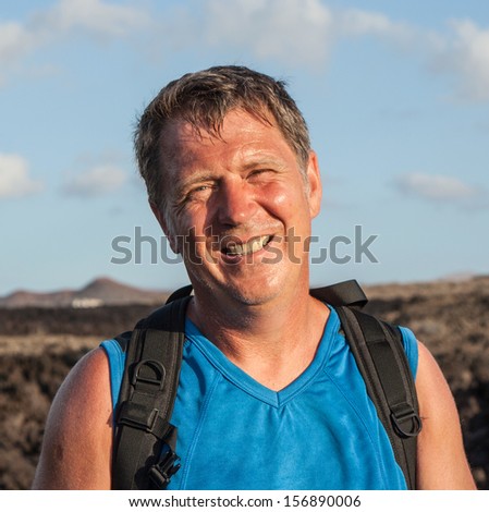 man on walking trail in volcanic area in Lanzarote looks happy