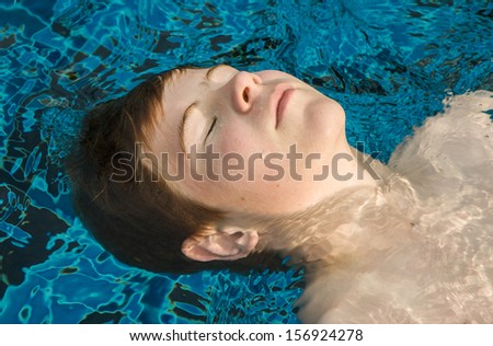 boy enjoys floating on his back in the pool
