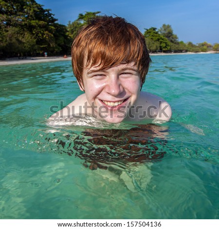 red haired boy enjoys the crystal clear water in the sea