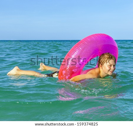 happy boy in a swim ring has fun in the ocean