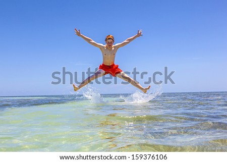handsome boy at a sandbank in the ocean jumps in the air
