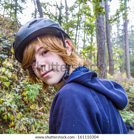 portrait of young teenage boy in forest with bike helmet