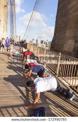 NEW YORK, USA - JULY 7: people exercise push-up at Brooklyn bridge late afternoon on July 7,2010, New York. Brooklyn Bridge was constructed under Roeblings 1840 patent for the spinning of wire rope.