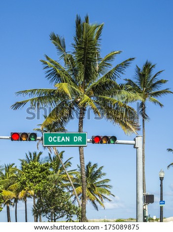 ocean drive sign in south beach with palms and red traffic light