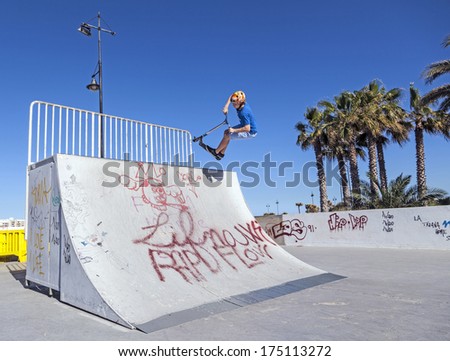 ARRECIFE, SPAIN - MARCH 29: boy jumps with his scooter over a ramp at the skate park on March 29, 2013 in Arrecife, Spain. The skate park was inaugurated in 2005 and is free of charge.