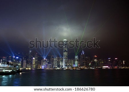 Hong Kong skyline at night with lights and skyscrapers over sea with laser beams