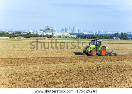 SULZBACH, GERMANY - SEP 12, 2009: tractor is running on the acre plowing the earth   in Sulzbach, Germany. The Rhein-Main area is caracterized by mixture between farming, industry and office Jobs.