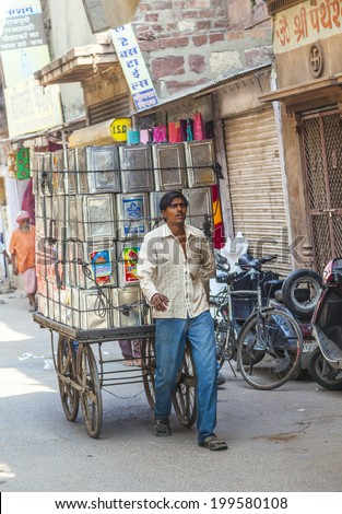JODHPUR, INDIA - OCTOBER 23, 2012: man transports goods  through the narrow roads in Jodhpur, India. Transportation by human push cars is stillpopular in the towns all over India.