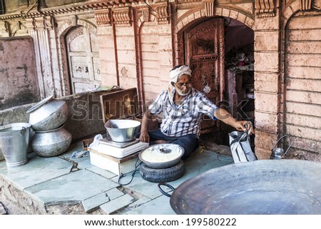 BIKANER, INDIA - OCT 24, 2012: man sells delicious curd in the streets of Bikaner, India. Curds are a dairy product obtained by curdling milk with rennet or any edible acidic substance.