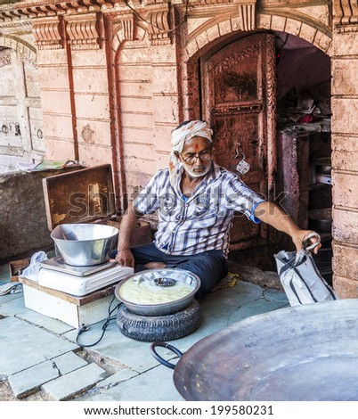 BIKANER, INDIA - OCT 24, 2012: man sells delicious curd in the streets of Bikaner, India. Curds are a dairy product obtained by curdling milk with rennet or any edible acidic substanc.