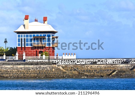 ARRIETA, SPAIN - DEC 26, 2010: Blue and red building containing the Museum of African Art and Culture on the black volcanic shore at Arrieta, Spain, also known as Blue House, or Casa Juanita.