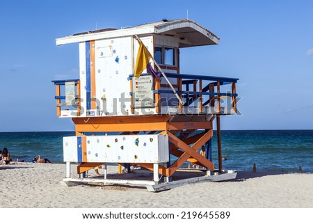 MIAMI, USA - AUG 23, 2014: People enjoy the beach next to a lifeguard tower in Miami, USA. South beach is famous for its wooden lifeguard towers which are designed in Art deco style.