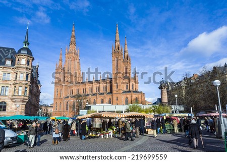 WIESBADEN, GERMANY - JAN 28, 2009: people enjoy the market at central market place in Wiesbaden, Germany. The market takes place in front of the Market church fromNew town hall from 1862.
