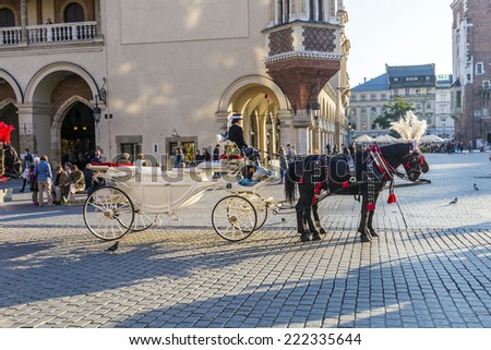 KRAKOW, POLAND - OCT 7, 2014: Horse carriages in front of Mariacki church on main square of Krakow city. Taking a horse ride in a carriage is very popular among tourists visiting Krakow
