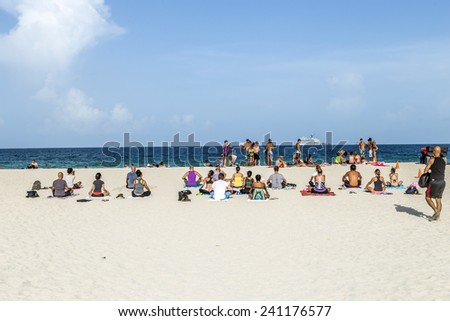 MIAMI, USA - AUGUST 18, 2014: People at the sea side meditate at the beach in Miami, USA. Miami Beach is a popular destination among tourists, spiking during the winter time.
