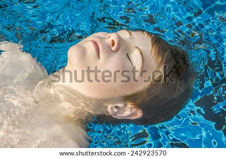 boy enjoys floating on his back in the pool