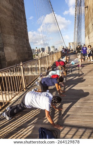 NEW YORK, USA - JULY 7, 2010: people exercise push-up at Brooklyn bridge in late afternoon in New York, USA. Brooklyn Bridge was constructed under Roeblings 1840 patent for the spinning of wire rope.