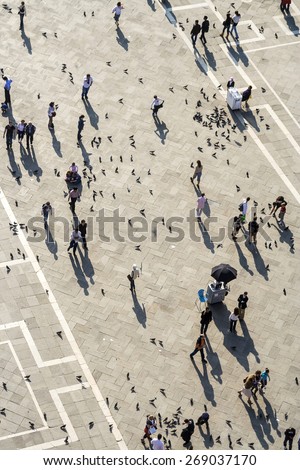 VENICE, ITALY - APR 11, 2007: Tourists on San Marco square feed large flock of pigeons. San Marco square is the largest and most famous square in Venice.