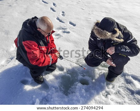 INARI, FINLAND - APR 2, 2015: tourists do ice fishing in Inari, Finland. The lake Inarijarvi and tours for 5 hour ice fishing are offered to tourists.